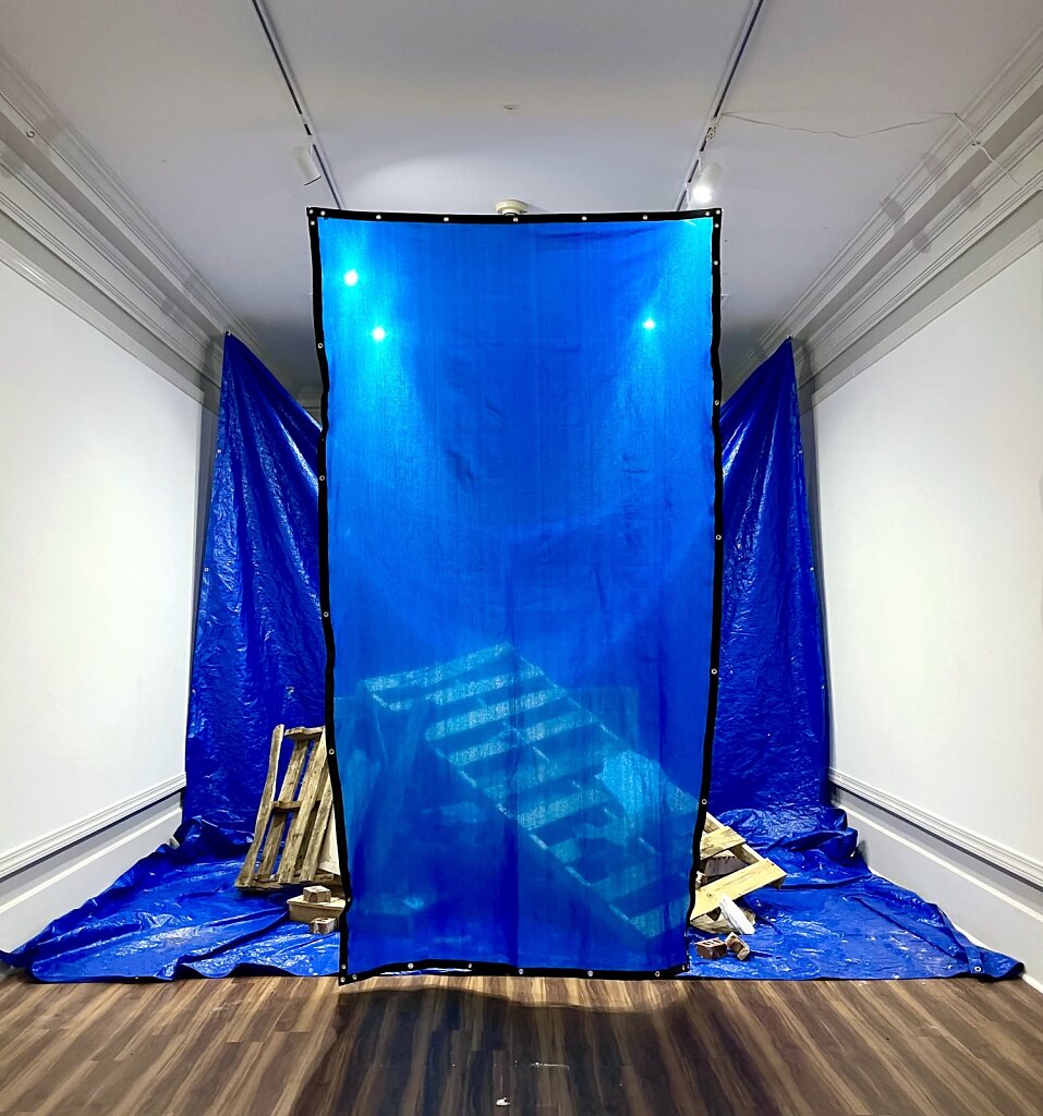 Material and Metaphor II, 2023;  tarp. construction mesh ( 11'x 6' ), found wooden pallets, dry wall.